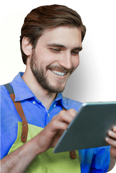 Homem sorrindo, olhando para o seu notebok. Camisa azul e macacão verde